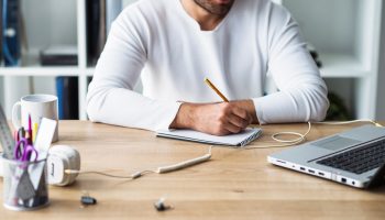 businessman-writing-notepad-wooden-desk (Large)