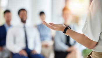 Leadership, presentation and hands of a manager in a conference for a meeting or training workshop. Coaching, staff and a speaker with a speech, talking and standing with employees for a seminar.