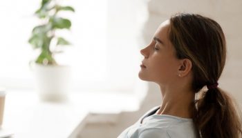 Side view young mixed race woman relaxing with closed eyes at workplace. Peaceful biracial lady freelancer deeply meditating, doing breathing exercises, enjoying break time, reducing stress at office.