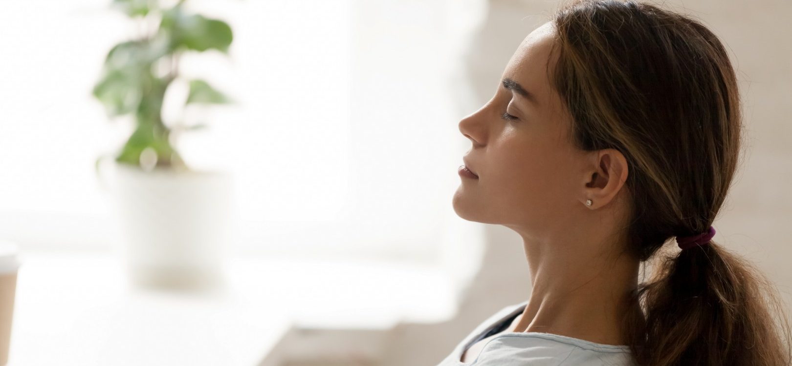 Side view young mixed race woman relaxing with closed eyes at workplace. Peaceful biracial lady freelancer deeply meditating, doing breathing exercises, enjoying break time, reducing stress at office.