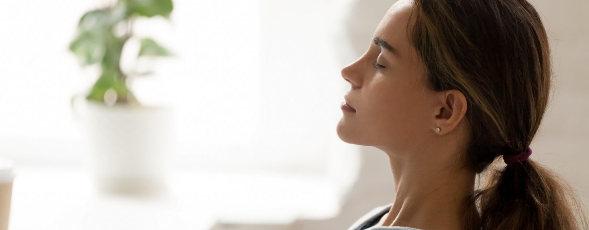 Side view young mixed race woman relaxing with closed eyes at workplace. Peaceful biracial lady freelancer deeply meditating, doing breathing exercises, enjoying break time, reducing stress at office.