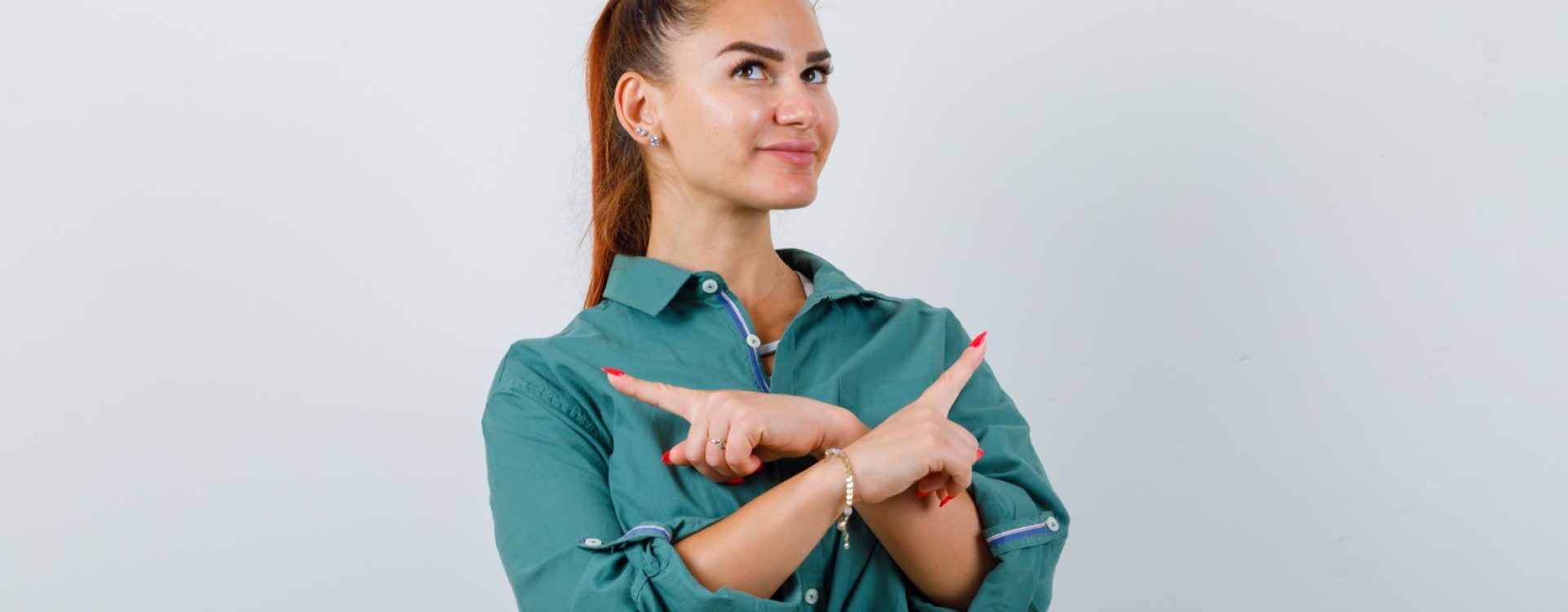 young woman pointing left and right, looking up in green shirt and looking hopeful. front view.